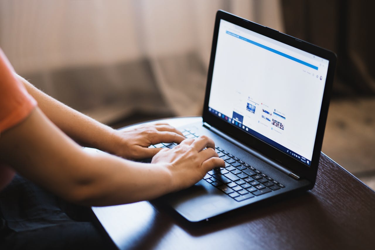 Close-up of person typing on a laptop indoors, showcasing technology use.